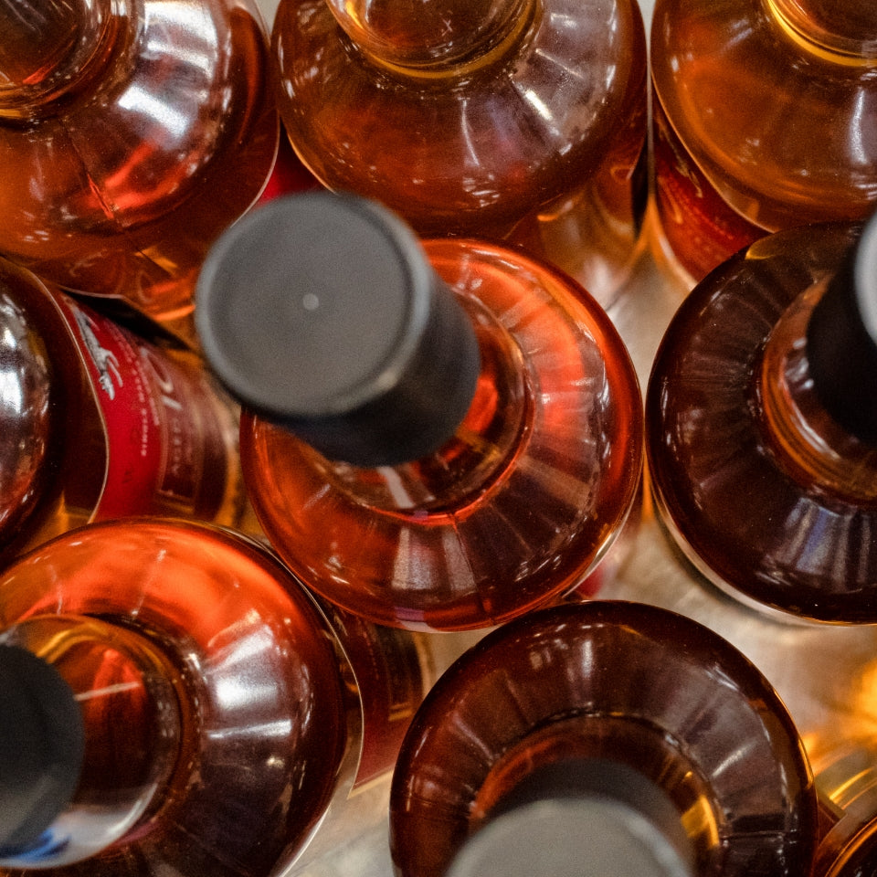 Close-up of whisky bottles with black caps on a white background