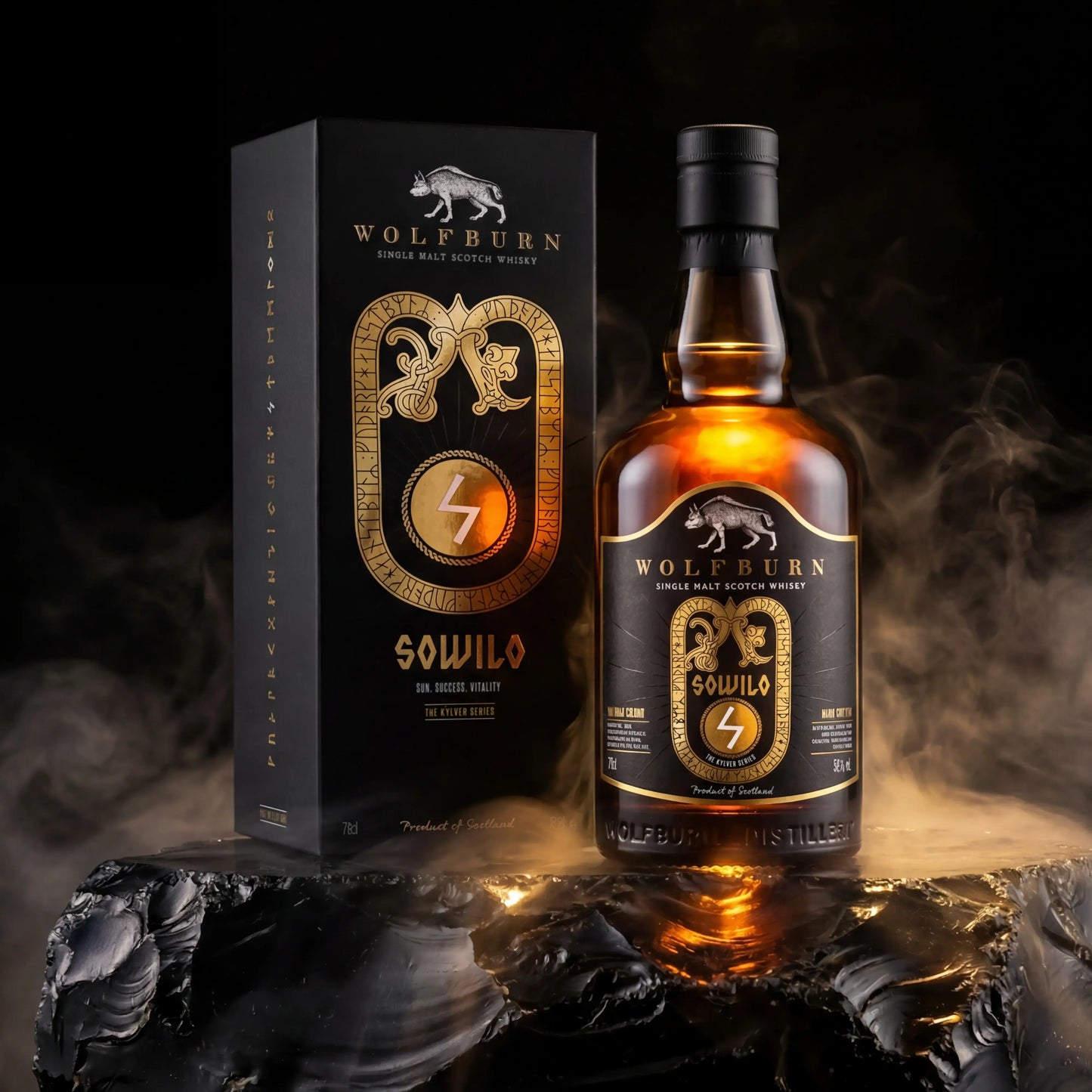 A bottle of Wolfburn Kylver Sowilo Single Malt Distilled Whisky stands beside its matching black and gold box on a dark reflective surface with dramatic smoke around it. The packaging and label feature a Wolfburn logo and ornate gold detailing, and the bottle contains amber-colored whisky.