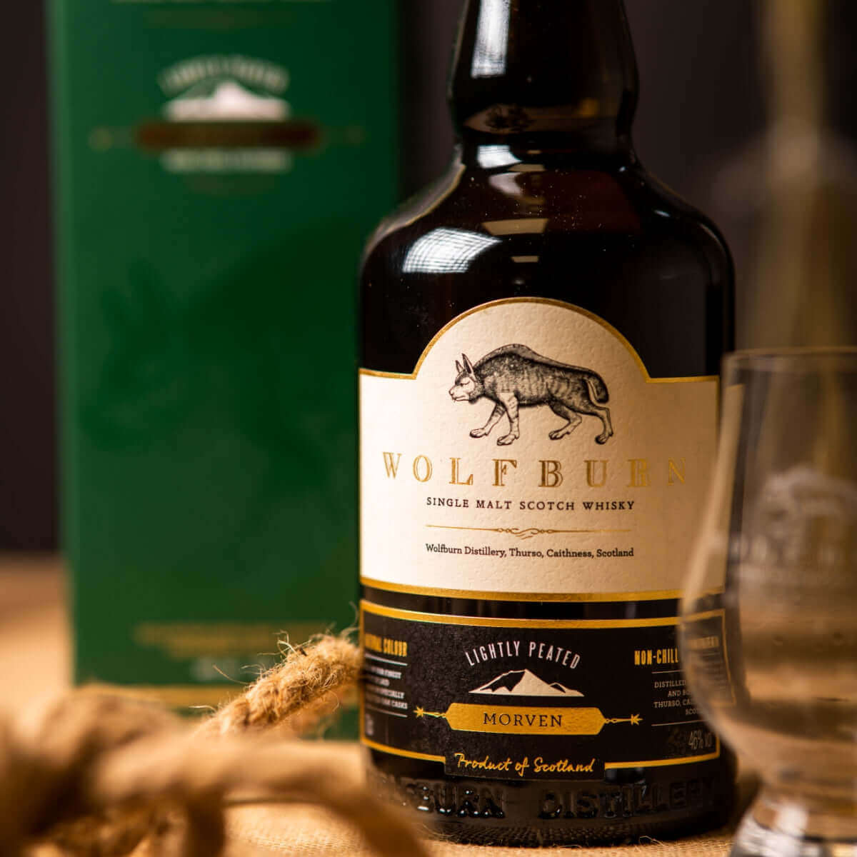 Wolfburn Single Malt Scotch Whisky bottle with lightly peated label and glass, featuring Morven, product of Scotland.