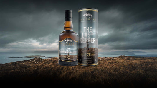 The Last Keeper Single Malt Scotch Whisky bottle and packaging against a scenic coastal background.