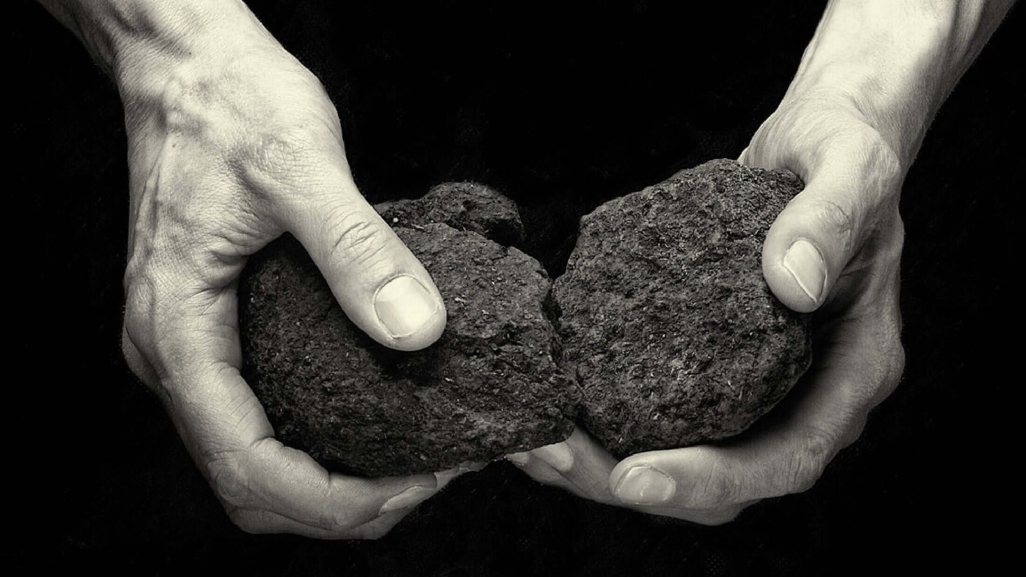 Two hands holding and splitting two rocks, representing natural elements in The Unexpected Story Behind Peated Whisky.