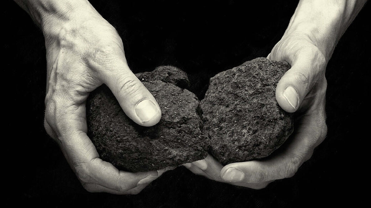 Two hands holding and splitting two rocks, representing natural elements in The Unexpected Story Behind Peated Whisky.