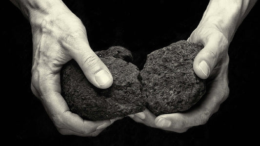 Two hands holding and splitting two rocks, representing natural elements in The Unexpected Story Behind Peated Whisky.