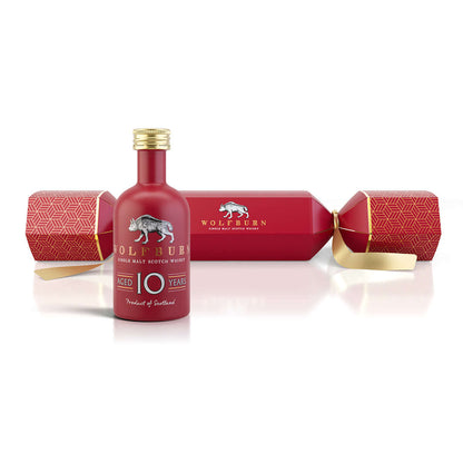Red bottle of Wolfburn whisky with decorative box on a white background