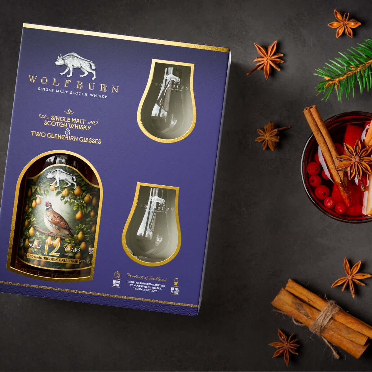 Wolfburn whisky gift set with two glasses on a dark surface with festive elements.
