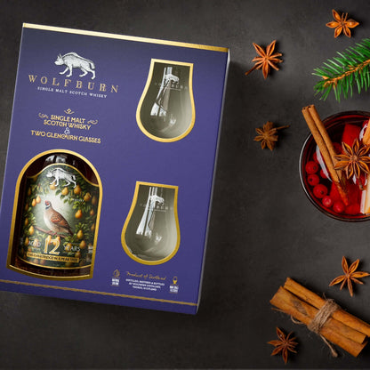 Wolfburn whisky gift set with two glasses on a dark surface with festive elements.