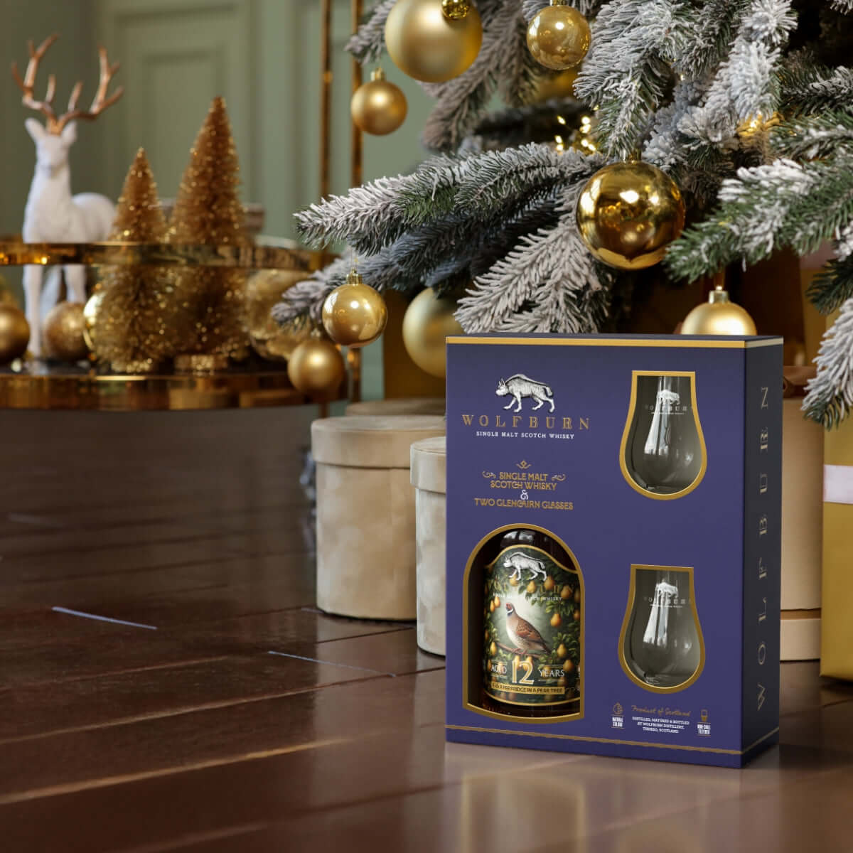 Wolfburn whisky gift set with two glasses in a decorative setting with Christmas tree and ornaments.
