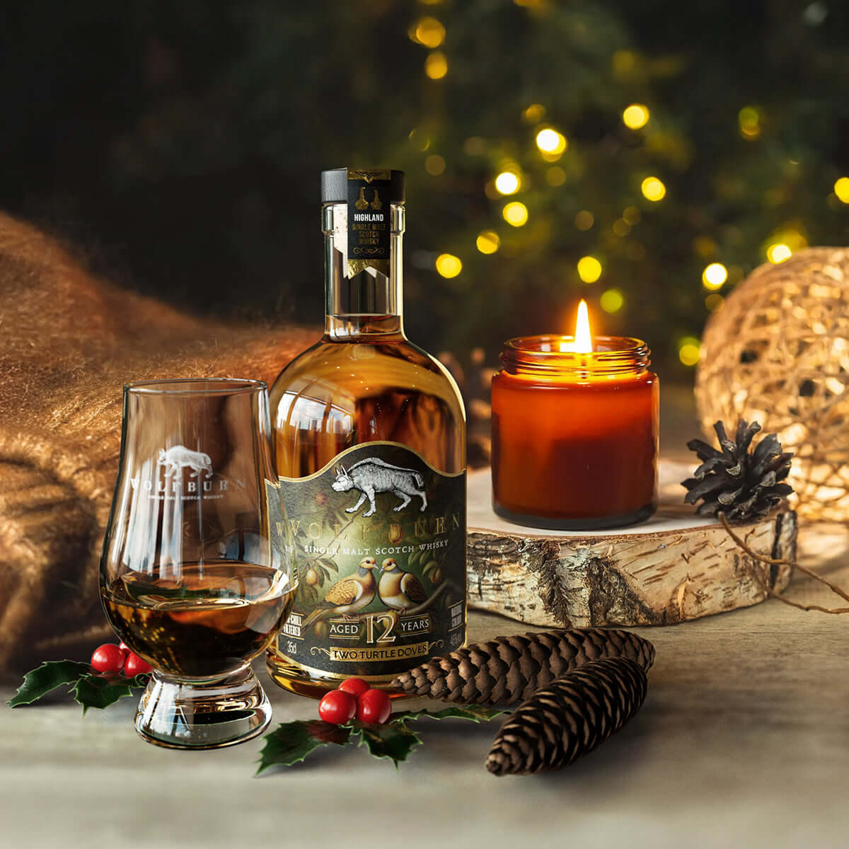 Bottle of Christmas whisky, glass, and candle on a wooden surface with festive decorations.