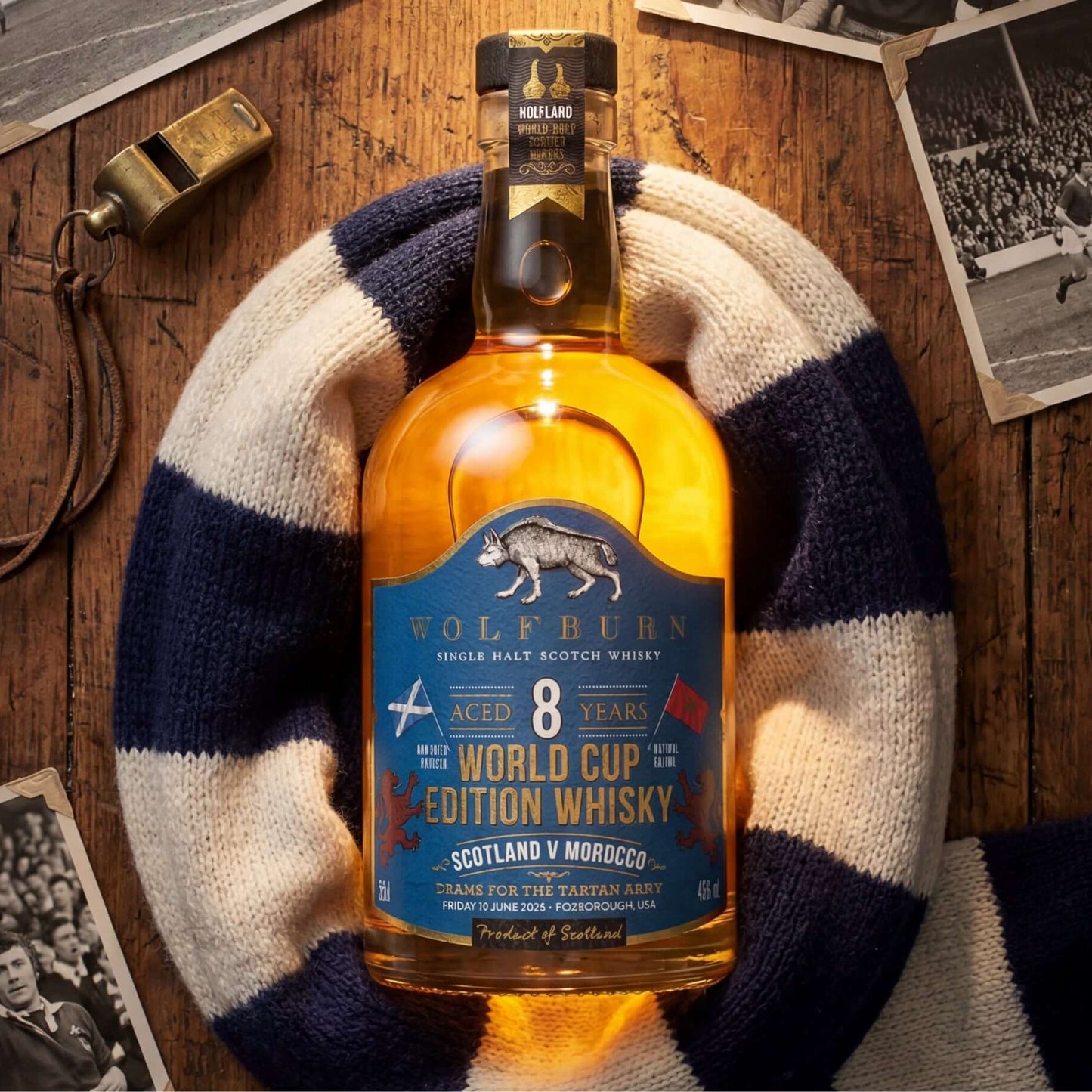 Wolfburn 8-year-old World Cup Single Malt Scotch Whisky Edition whisky bottle on a wooden surface with vintage photos and a scarf.
