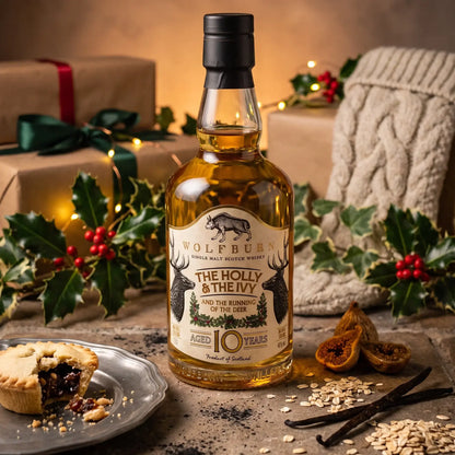 Wolfburn The Holly and The Ivy Christmas single malt whisky with a mince pie, dried figs and vanilla pods on a festive table with presents.