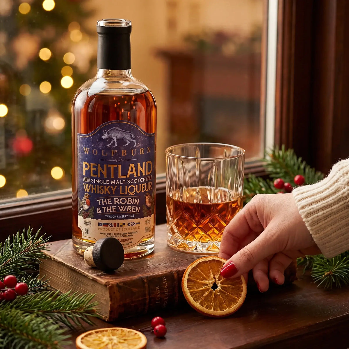 The Robin and The Wren Pentland Christmas whisky liqueur poured by the window with dried orange and winter greenery